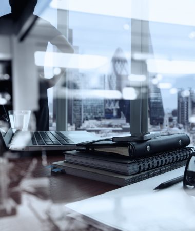double exposure of business documents on office table with smart phone and digital tablet and london city blurred view and man thinking in the background